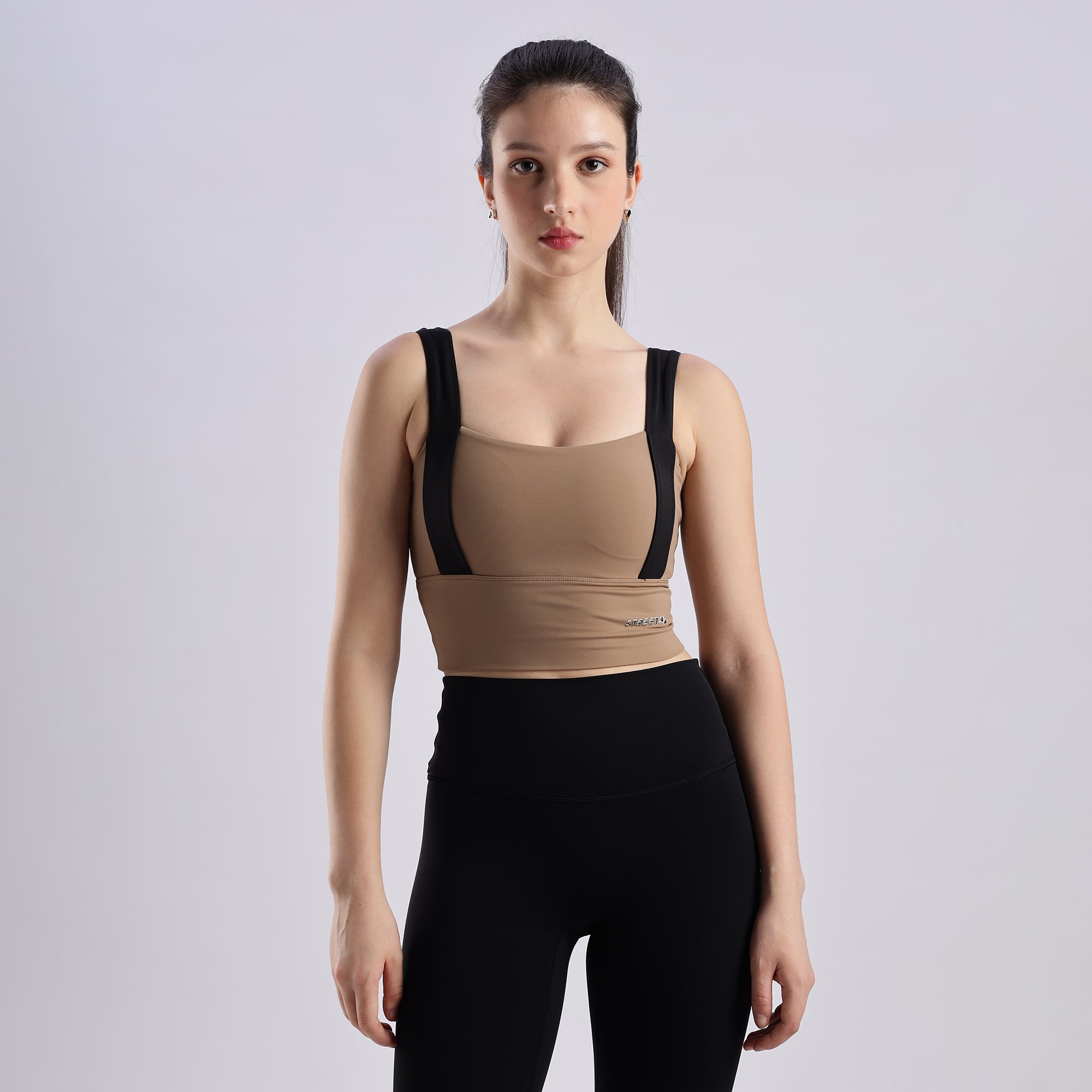 A woman wearing a Evoke Sports Bra with black straps and black leggings.
