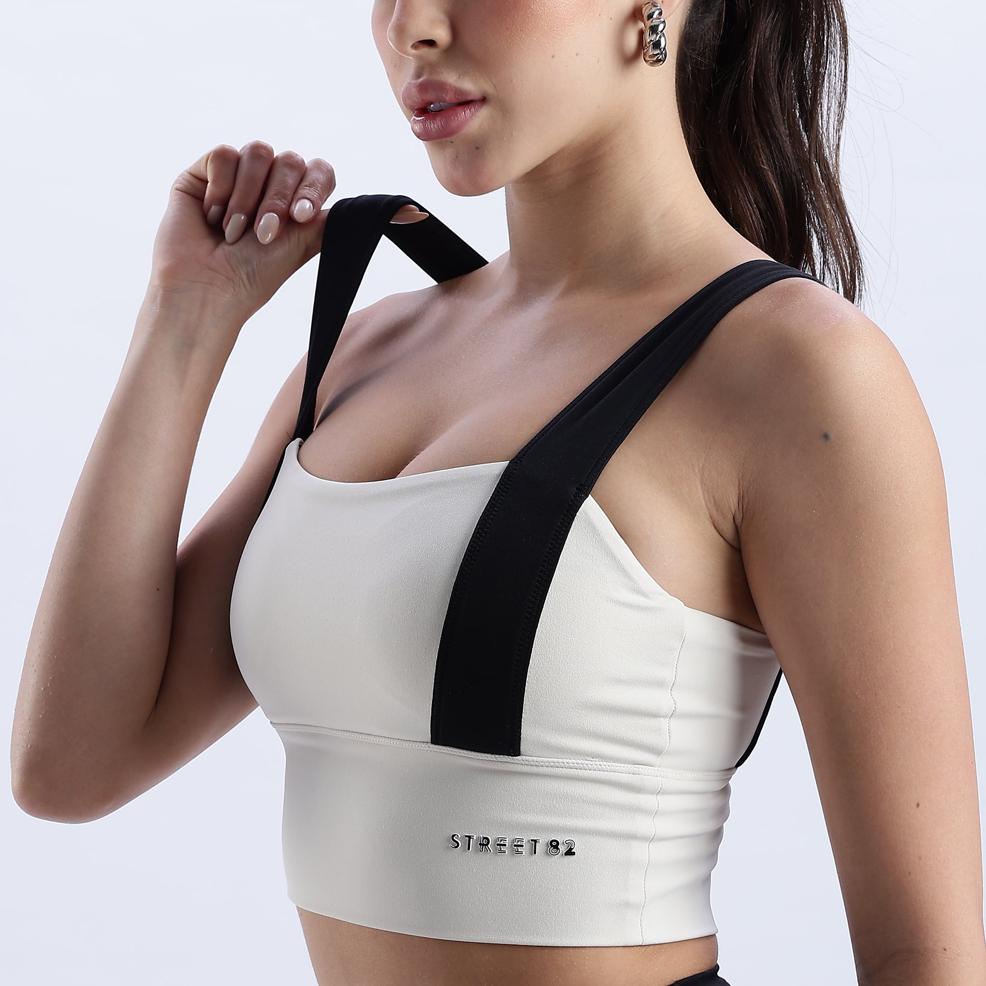 Close up of Woman wearing a white Evoke Sports Bra with black straps.